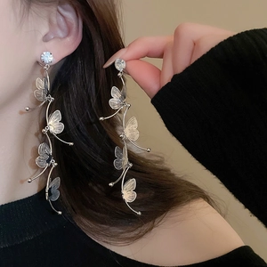 Close-up of elegant silver butterfly tassel earrings with sparkling rhinestones on model