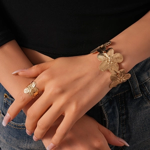 Detail shot of gold floral metal bangle and ring set with fine radial texture finish
