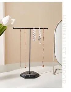 Detail of T-bar jewelry stand with black matte metal and hexagonal marble base on a vanity