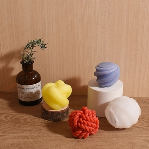 Bougies parfumées artistiques aux formes de nœuds et spirales sur socle en bois clair