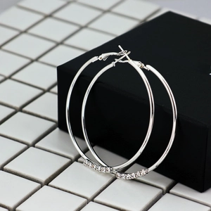 Oversized silver hoop earrings with delicate crystals on a minimalist polished surface