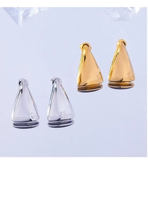 Macro shot of polished gold and silver triangle stud earrings reflecting on a mirror