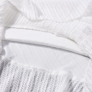 Vue détaillée du tissu en dentelle crochetée blanche montrant la texture ajourée et doublure