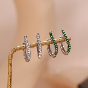 Silver swirl earrings with green and white pavé cubic zirconia on golden display stand