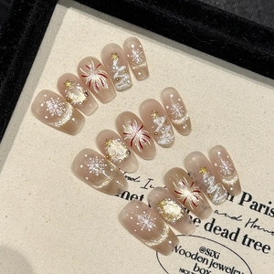 Detail of handmade Christmas press-on nails with snowflakes, star charms and cat eye glitter