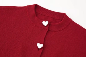 Detail of silver heart-shaped buttons on a dark red knit cardigan with round neck