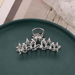 Silver metal hair claw clip with five hollow star design on elegant green plate