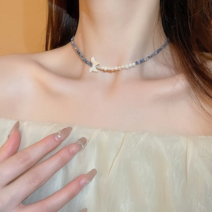 Détail d'un collier en perles d'eau douce avec pendentif queue de poisson sur un mannequin