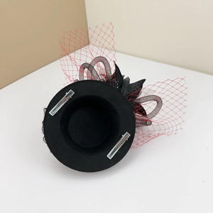 Detail view of mini black hat fascinator with red mesh veil and dual metal hair clips