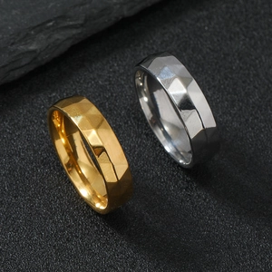 Macro detail of geometric faceted gold and silver stainless steel rings on stone background