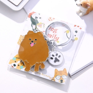 Cartoon Pomeranian metal keychain with paw charm and enamel finish on white background