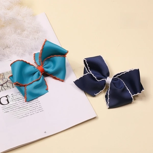 Detail of teal and navy blue grosgrain ribbon bow hair clips with contrast stitching