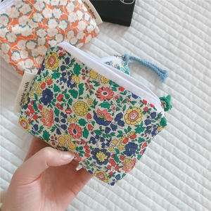 Close-up of floral cotton mini pouch with white zipper and colorful woven puller