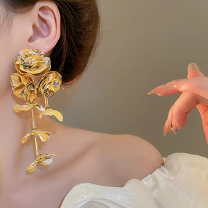 Detail of yellow floral chiffon fabric tassel earrings worn by a model in close-up view
