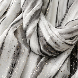 Detail of linen-feel scarf featuring black and white tie-dye with gold foil accents