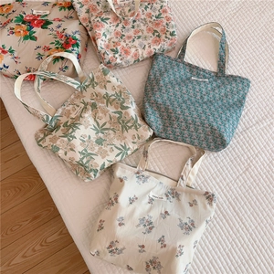 Flat lay of five cotton tote bags with vintage floral prints and zip closures