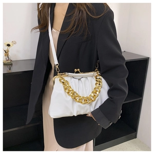 Detail of white pleated cloud bag with gold chunky chain strap worn over black blazer