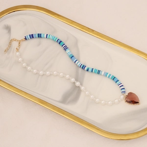 Detail of bohemian pearl necklace with blue striped clay beads and heart pendant