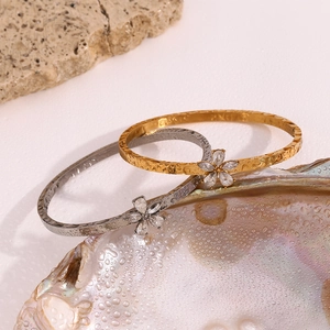 Detail of 18K gold and silver plated flower bracelets with crystals on a textured shell