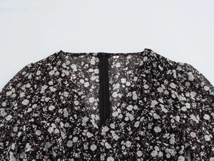 Detail of V-neckline and back zipper on black floral maxi dress with small flower patterns
