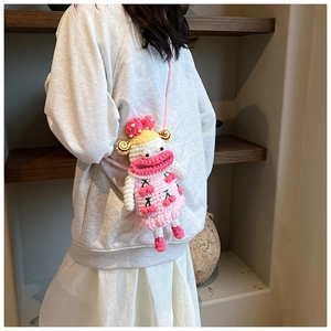 Detail of pink knitted crossbody bag featuring cherry patterns and a cute doll design