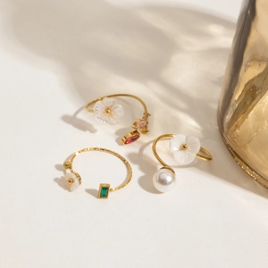 Detailed view of adjustable 18K gold-plated rings with pearls and colorful gemstones