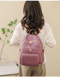 Vista posteriore di una donna con un grande zaino rosa malva con tasche multifunzione