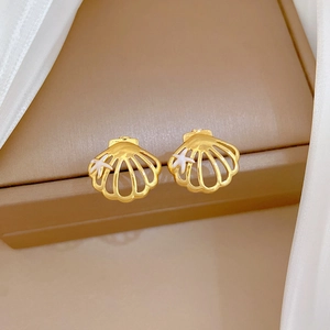 Detailed close-up of gold shell earrings with small starfish on white silk background