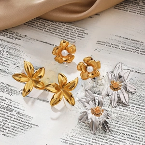 Elegant 18k gold sunflower and pearl earrings set on vintage book backdrop