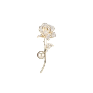 Detailed macro view of a rose brooch with inlaid crystals and a large pearl on white background