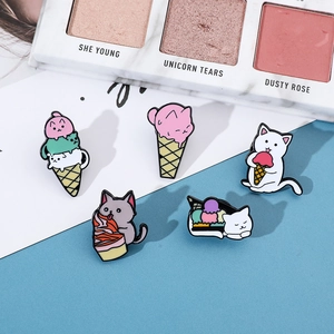 Detail of five cute cartoon enamel cat and ice cream pins on a white decorative surface