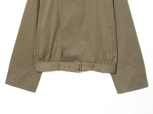 Detailed view of khaki cropped trench coat with metallic belt buckle and fine stitching