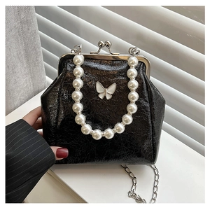 Detail of black embossed leather bag featuring pearl handle and butterfly metal ornament