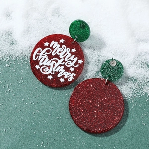 Detail of red and green glittery Merry Christmas earrings on a snowy background