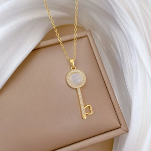 Macro shot of gold key pendant with opal stone and heart detail on a leather box