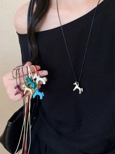 Detail shot of colorful horse pendants in silver, gold, and red on a black necklace cord