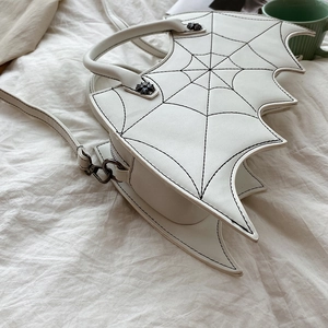 Close-up of white bat-wing handbag featuring black spiderweb embroidery on PU leather