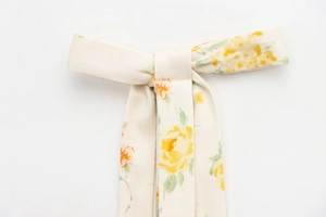 Nahaufnahme einer cremefarbenen Schleife mit feinem floralen Muster in Orange