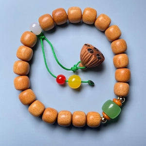 Detail of sandalwood lotus bracelet with vibrant accent beads on a smooth blue surface