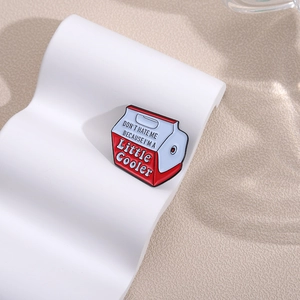 Milk carton enamel pin with little cooler text on a white wavy pedestal display