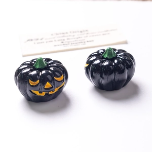 Macro shot of two small glow-in-the-dark Halloween pumpkin beads with jack-o-lantern face