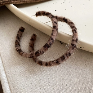 Detail view of plush leopard print C-shape hoop earrings with vintage brown faux fur texture