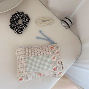 Close-up of floral quilted mini pouch with leopard scrunchie and crochet hair clip