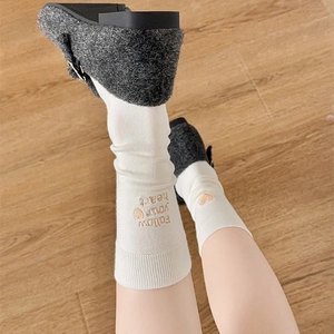 Detail of white cotton socks with gold embroidered heart and follow your heart text