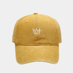 Detailed close-up of crown embroidery on a mustard yellow washed cotton baseball cap
