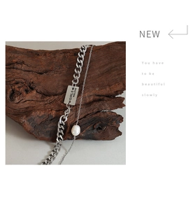 Detail of layered silver chain necklace with rectangular pendant and freshwater pearl