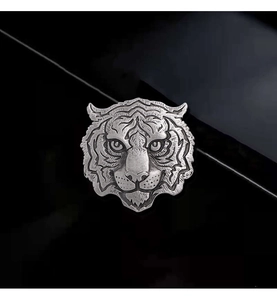 Macro shot of silver tiger head relief badge with detailed metal texture on black surface
