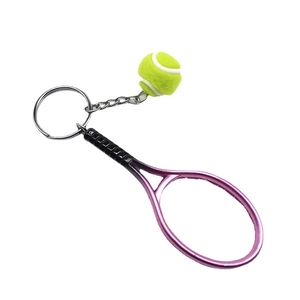 Pink metal tennis racket and yellow ball keychain charm on a polished silver ring