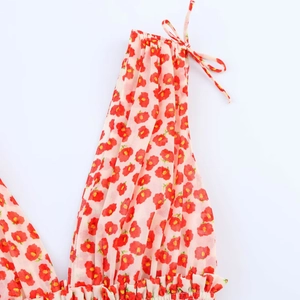 Macro detail van rode bloemenprint op roze chiffon jurk met strikbandjes en plooirand