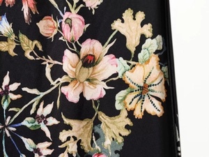 Detailed macro view of vibrant floral prints on smooth black satin fabric for casual suits